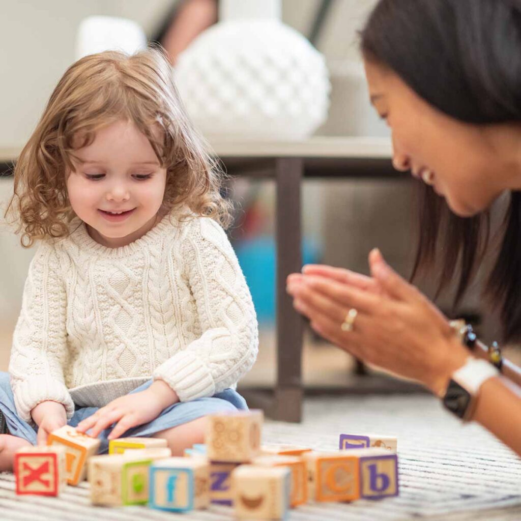 Smiling female therapist working with preschooler using educational development toys.